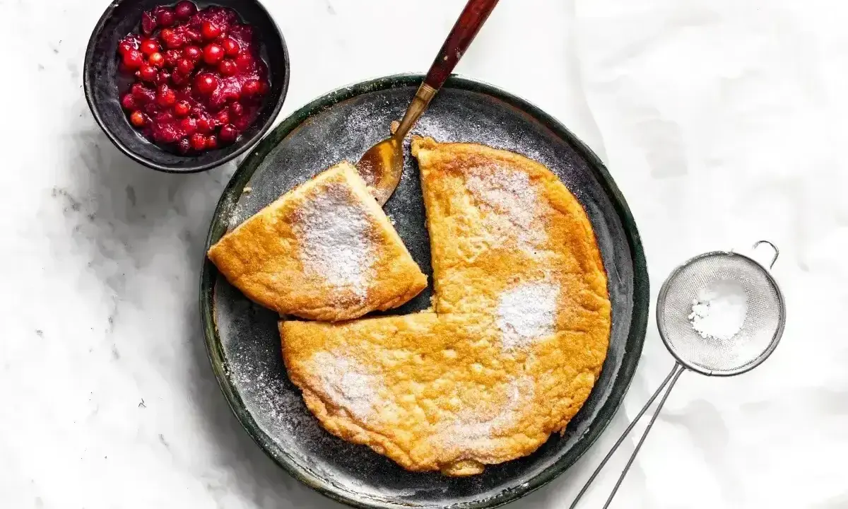 Puszysty omlet z air fryera, posypany cukrem pudrem, podany z żurawiną. Idealny na śniadanie.