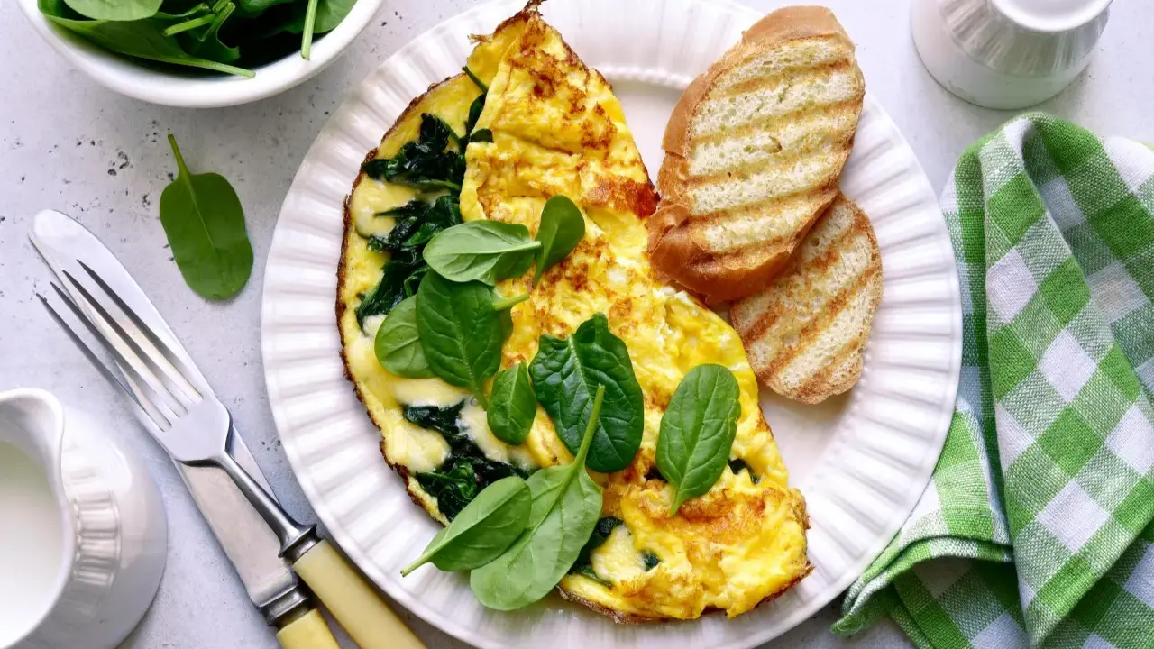Pyszny omlet ze szpinakiem, podany z grzankami i świeżymi liśćmi szpinaku. Idealne śniadanie!