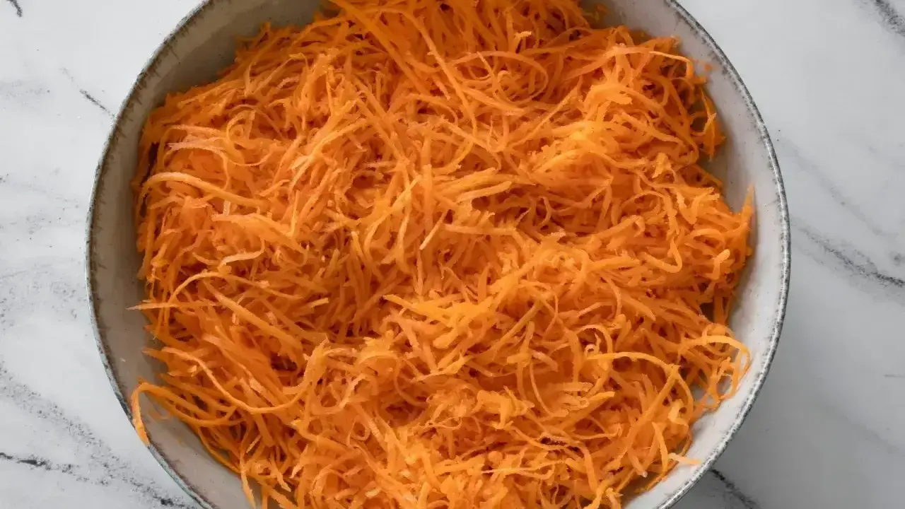 Miseczka pełna startej marchewki, wyglądająca jak surówka z marchewki jak z restauracji. Idealna baza do zdrowego posiłku.