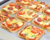 Pyszne, domowe pizza z chleba tostowego z serem, pomidorami i kiełbasą, gotowa do pieczenia.
