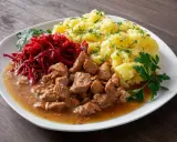 Gulasz z łopatki, ziemniaki z koperkiem i surówka z buraczków na białym talerzu.