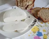 Domowy ser z mleka, pokrojony w plastry, na talerzyku z chlebem. Idealny na śniadanie.