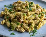 Pyszny makaron z kurczakiem, brokułami i suszonymi pomidorami, posypany parmezanem i natką pietruszki.