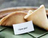 Dwa ciastka z wróżbą na zielonej serwetce. Jedno z nich ma w środku karteczkę z napisem "I love you!".