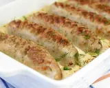 Biała kiełbasa w sosie chrzanowym, zapieczona w naczyniu, ozdobiona koperkiem. Pyszne danie gotowe do podania.