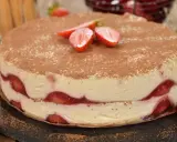 Pyszne ciasto z truskawkami, przełożone kremem i posypane kakao. Idealne na letnie popołudnie.