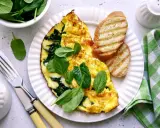 Pyszny omlet ze szpinakiem, podany z grzankami i świeżymi liśćmi szpinaku. Idealne śniadanie!