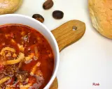 Aromaticzne flaki po zamojsku w białej misce, obok bułki i gałki muszkatołowej.