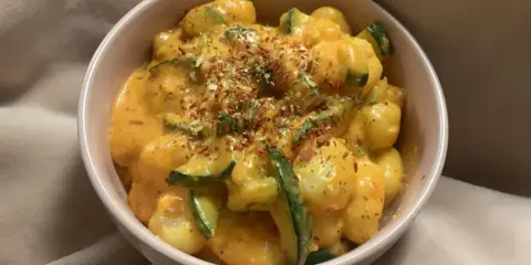 Pyszne gnocchi z kremowym, pomarańczowym sosem i kawałkami cukinii, posypane ziołami. Idealne danie na szybki obiad.
