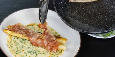 Naleśniki ze szparagami i chrupiącym boczkiem, przygotowywane na patelni.
