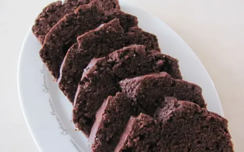 Pokrojona babka z kakao, ułożona na białym talerzu, kusi wilgotnym, ciemnym wnętrzem.