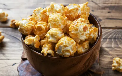 Pyszny karmelowy popcorn w drewnianej misce. Idealny do domowego seansu, gdy wiesz, jak zrobić popcorn w garnku.