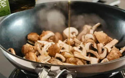 Olej wlewany na patelnię z pieczarkami i cebulą. Prosty sposób, jak usmażyć pieczarki na złoto.