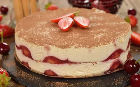 Pyszne ciasto z truskawkami, przełożone kremem i posypane kakao. Idealne na letnie popołudnie.