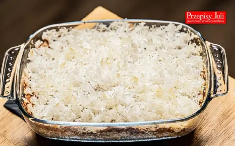 Zapiekanka z ryżem i jabłkami w szklanym naczyniu, gotowa do pieczenia.
