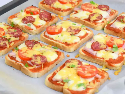 Pyszne, domowe pizza z chleba tostowego z serem, pomidorami i kiełbasą, gotowa do pieczenia.