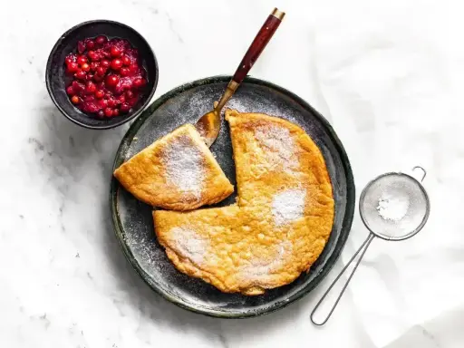 Puszysty omlet z air fryera, posypany cukrem pudrem, podany z żurawiną. Idealny na śniadanie.