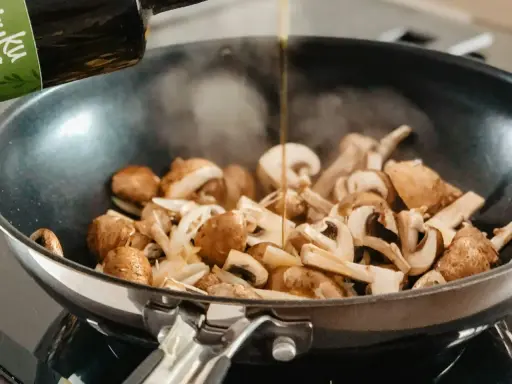 Olej wlewany na patelnię z pieczarkami i cebulą. Prosty sposób, jak usmażyć pieczarki na złoto.