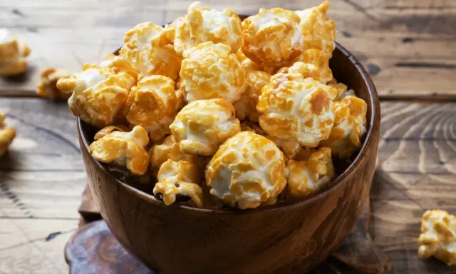 Pyszny karmelowy popcorn w drewnianej misce. Idealny do domowego seansu, gdy wiesz, jak zrobić popcorn w garnku.