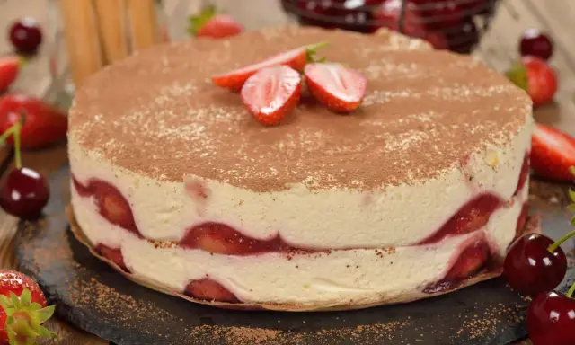 Pyszne ciasto z truskawkami, przełożone kremem i posypane kakao. Idealne na letnie popołudnie.