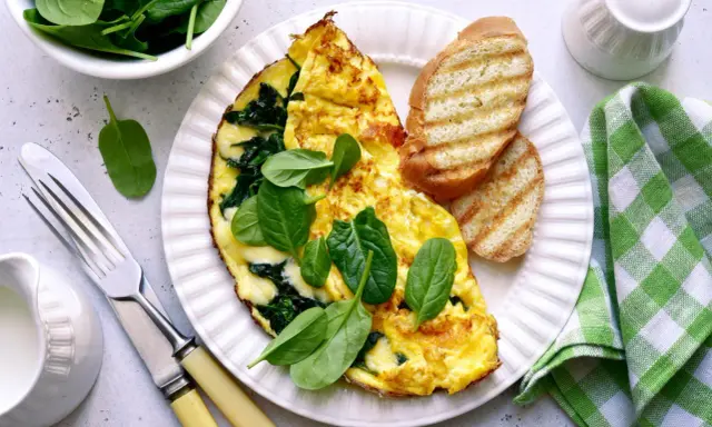 Pyszny omlet ze szpinakiem, podany z grzankami i świeżymi liśćmi szpinaku. Idealne śniadanie!