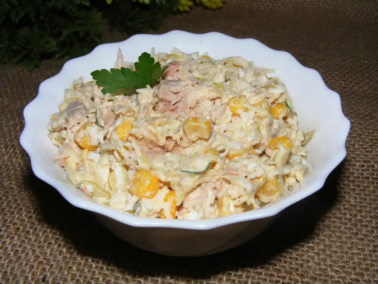 Pyszna sałatka z tuńczykiem, kukurydzą i jajkiem, udekorowana natką pietruszki. Idealna na szybki lunch.