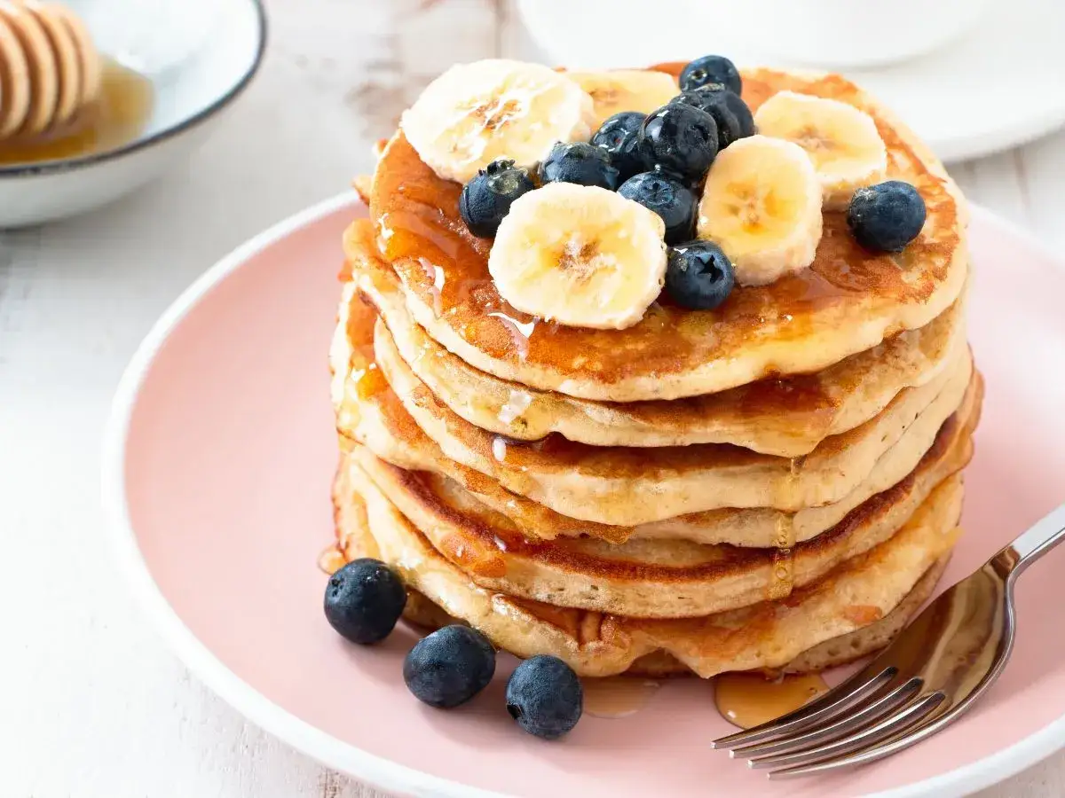 Pyszny stos pancake'&oacute;w z bananem i bor&oacute;wkami, polany syropem. Idealny przepis na śniadanie.