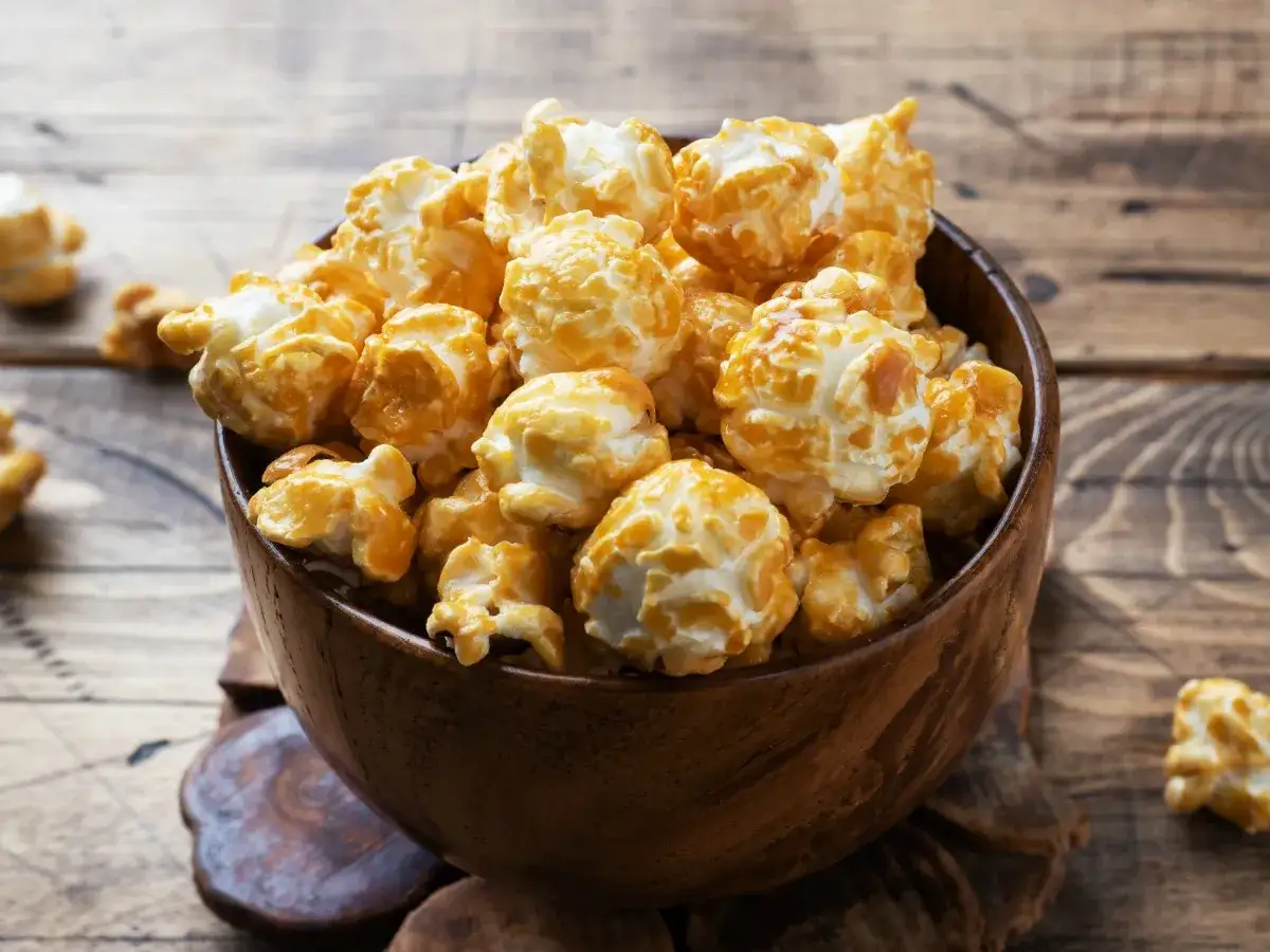 Jak zrobić popcorn w garnku? Pyszny, karmelowy popcorn w drewnianej misce, gotowy do chrupania.