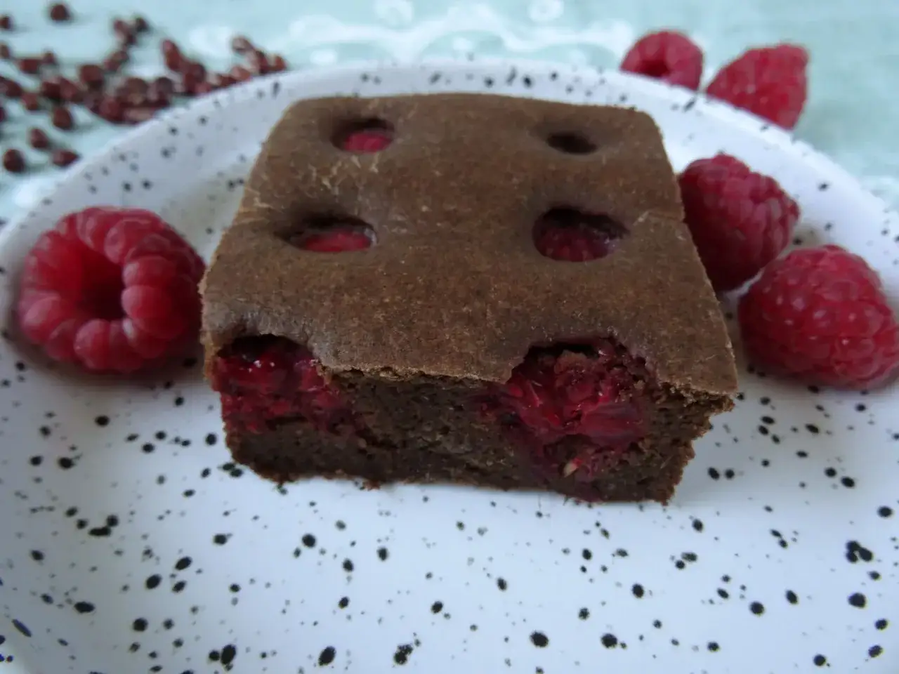 Pyszny brownie z fasoli z malinami, ozdobione świeżymi owocami.
